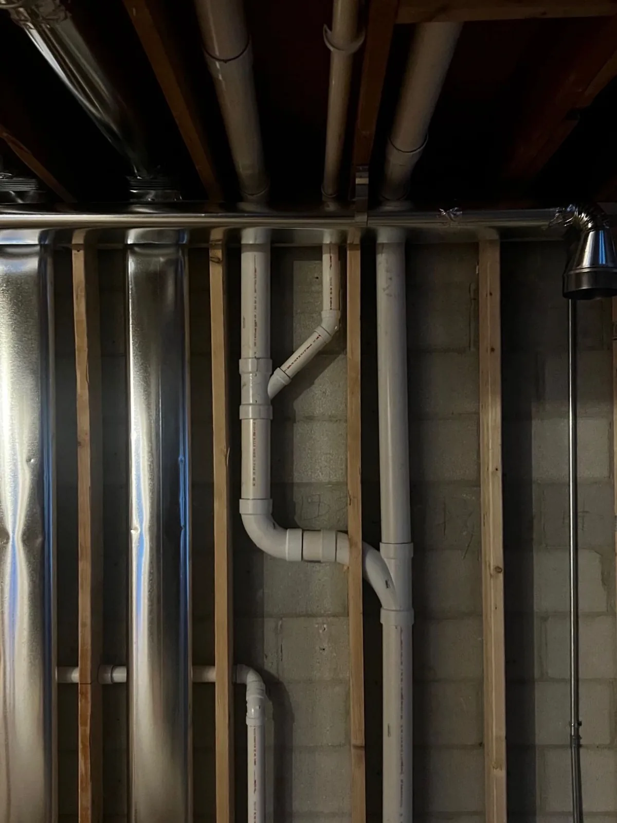 PVC drain and vent stack against a basement block wall