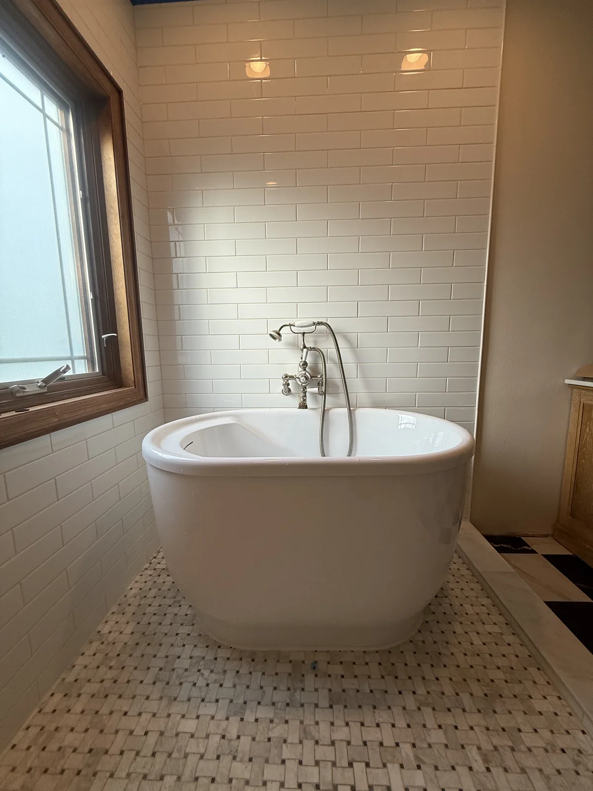 Freestanding soaking tub with a wall-mounted faucet